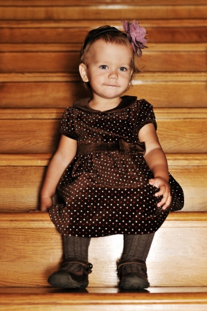 fashion 1 year girl sitting on the wooden stairsの写真素材