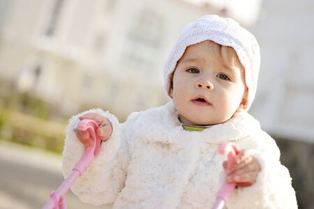 baby girl playing  with a stroller outdoorsの写真素材