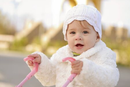 walking baby girl with toy pramの写真素材