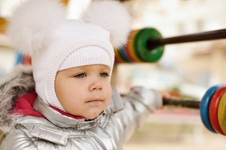 fashion winter girl wearing fur bobble hat on the playgroundの写真素材