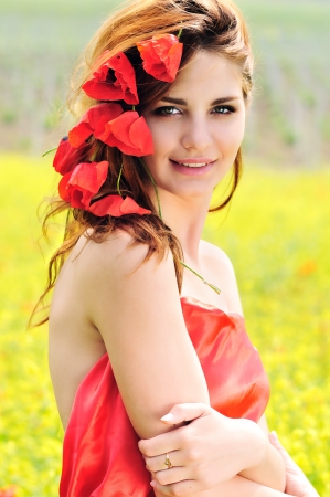 smiling girl standing with poppies in her hairの写真素材