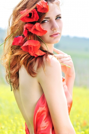 tender lady standing with poppies in her hairの写真素材