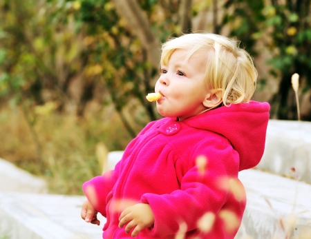 baby girl eating corn curls outdooorsの写真素材