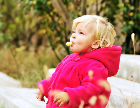 baby girl eating corn curls outdooorsの写真素材