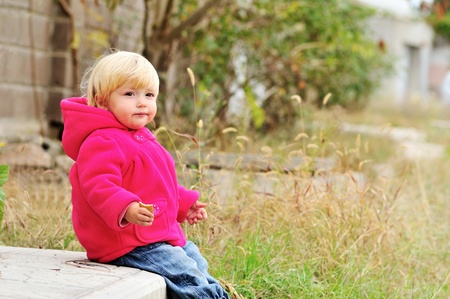 baby girl eating cake and sitting on the thresholdの写真素材