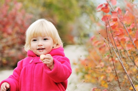 bright blonde baby girl walking in fall parkの写真素材