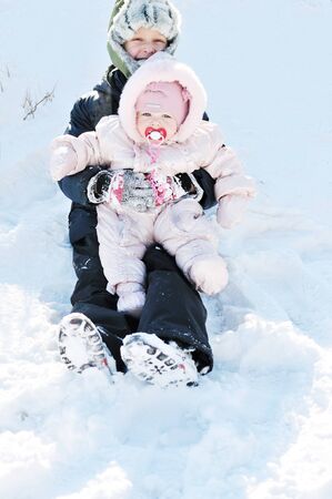 baby girl with brother having fun in snowの写真素材