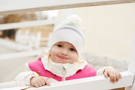 toddler girl showing tongue near fenceの写真素材