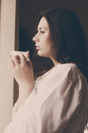 young woman with morning coffee near the windowの写真素材