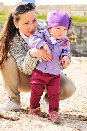 mother helping her baby girl to do first stepsの写真素材
