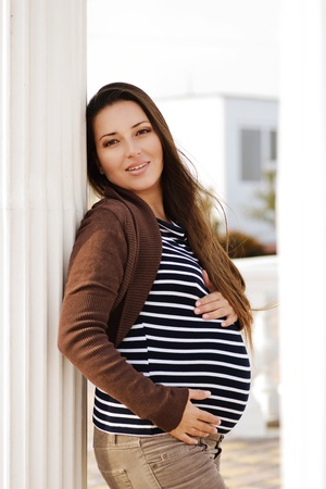 longhaired brunette  pregnant woman near the columnの写真素材
