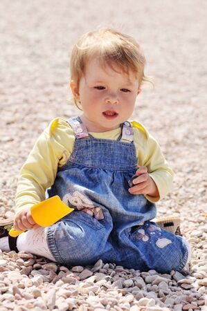 playing baby girl sitting on the pebbleの写真素材