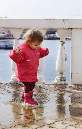 happy childhood of baby girl walking in puddleの写真素材