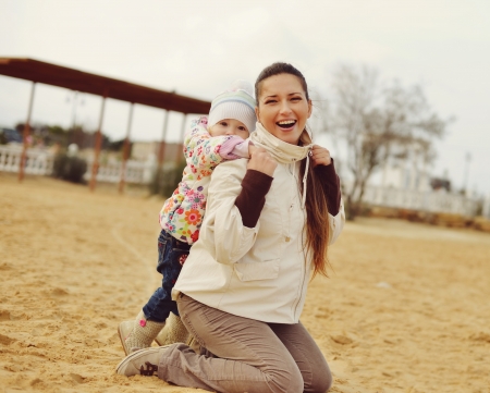 pregnant mother with baby daughter having fun on beachの写真素材