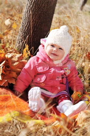 baby in fall time sitting under the treeの写真素材