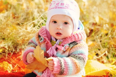 baby in fall time sitting under with leafの写真素材