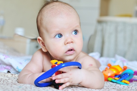 sweet blue-eyed baby laying with toysの写真素材