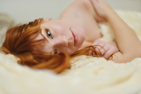 redhead young woman laying in bedの写真素材