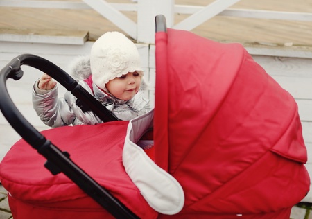cunning toddler girl looking into the pram with babyの写真素材