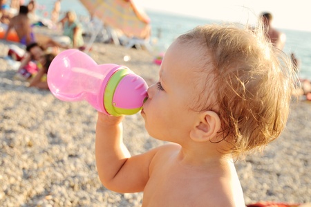 baby drinking water on the beachの写真素材