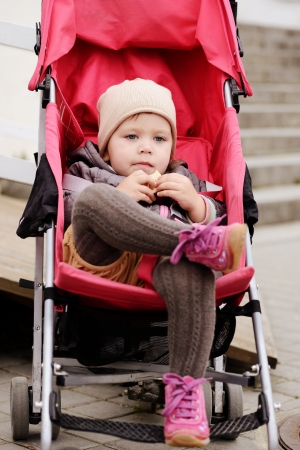 such a cute toddler girl sitting in the strollerの写真素材