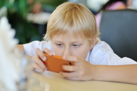 blonde boy playing phone at homeの写真素材