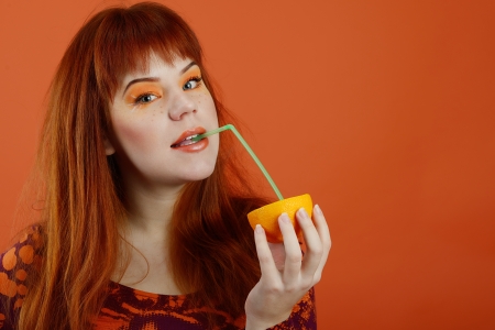 girl with orange drinking juice through the strawの写真素材