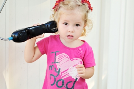 toddler girl speaking on the paystation - not a trade mark on the shirtの写真素材