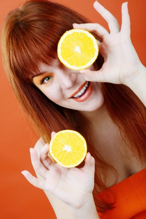 redhead girl with orange near her eyesの写真素材