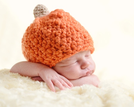 sweet newborn wearing orange hatの写真素材
