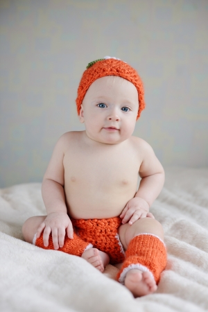 adorable baby sitting on the sofa in orange costumeの写真素材