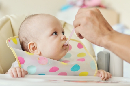 father feeding 6 months old baby with spoonの写真素材