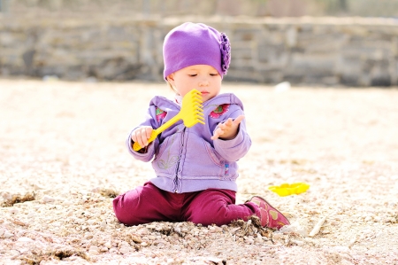 playing baby girl sitting with rakeの写真素材