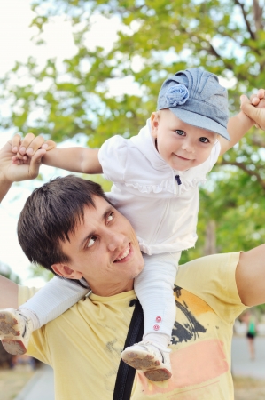 Young father with her baby  daughter up on shouldersの写真素材
