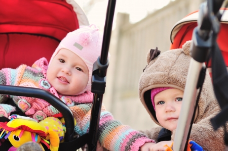 two baby girls sitting in strollers and lookingの写真素材