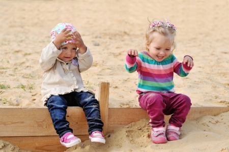 happy toddlers sitting in sandの写真素材