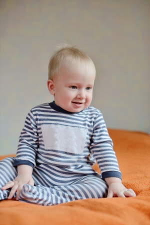 baby wearing striped sleepwear sitting on the sofaの写真素材