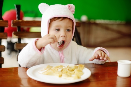 toddler girl eating pancakes in outdoor cafeの写真素材