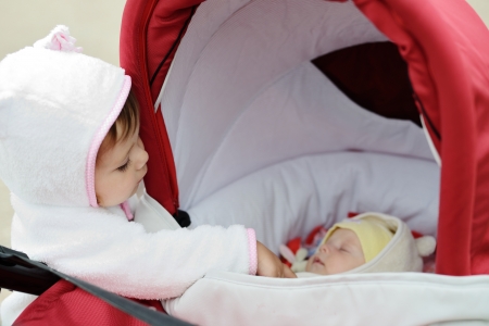 cunning toddler girl looking into the pram with babyの写真素材