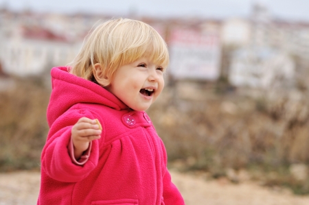 laughing toddler girl runnung on the walkの写真素材