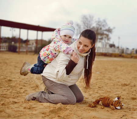 pregnant mother with baby daughter having fun on beachの写真素材