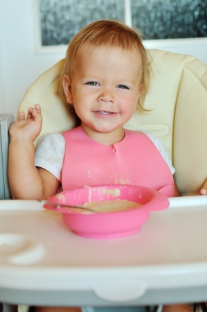 happy eating baby girl in chairの写真素材