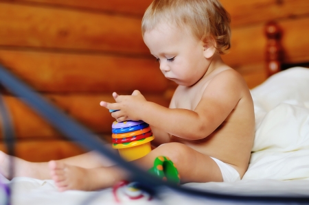 toddler with toy sitting on the bedの写真素材