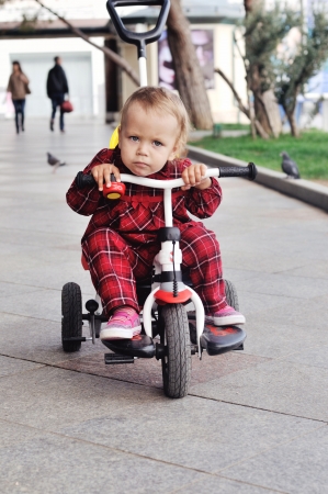 baby girl on her  tricycle on the walkの写真素材