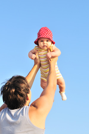 father holding three months baby over the blue skyの写真素材