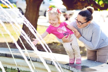 happy pregnant mother with baby girl near the fountainの写真素材