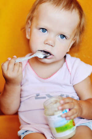 baby girl eating puree from jar on her ownの写真素材
