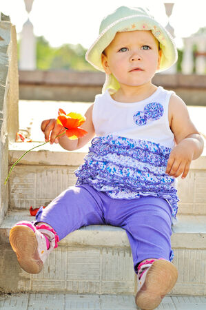 baby with  flower sitting on the stairの写真素材