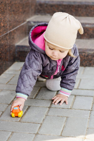 toddler girl playing toy car outdoorsの写真素材