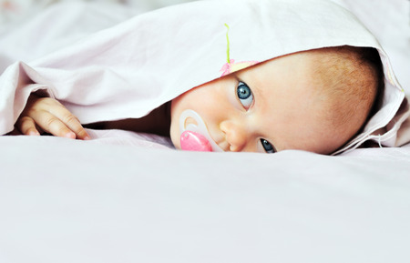 3 months old baby looking out under the blanketの写真素材